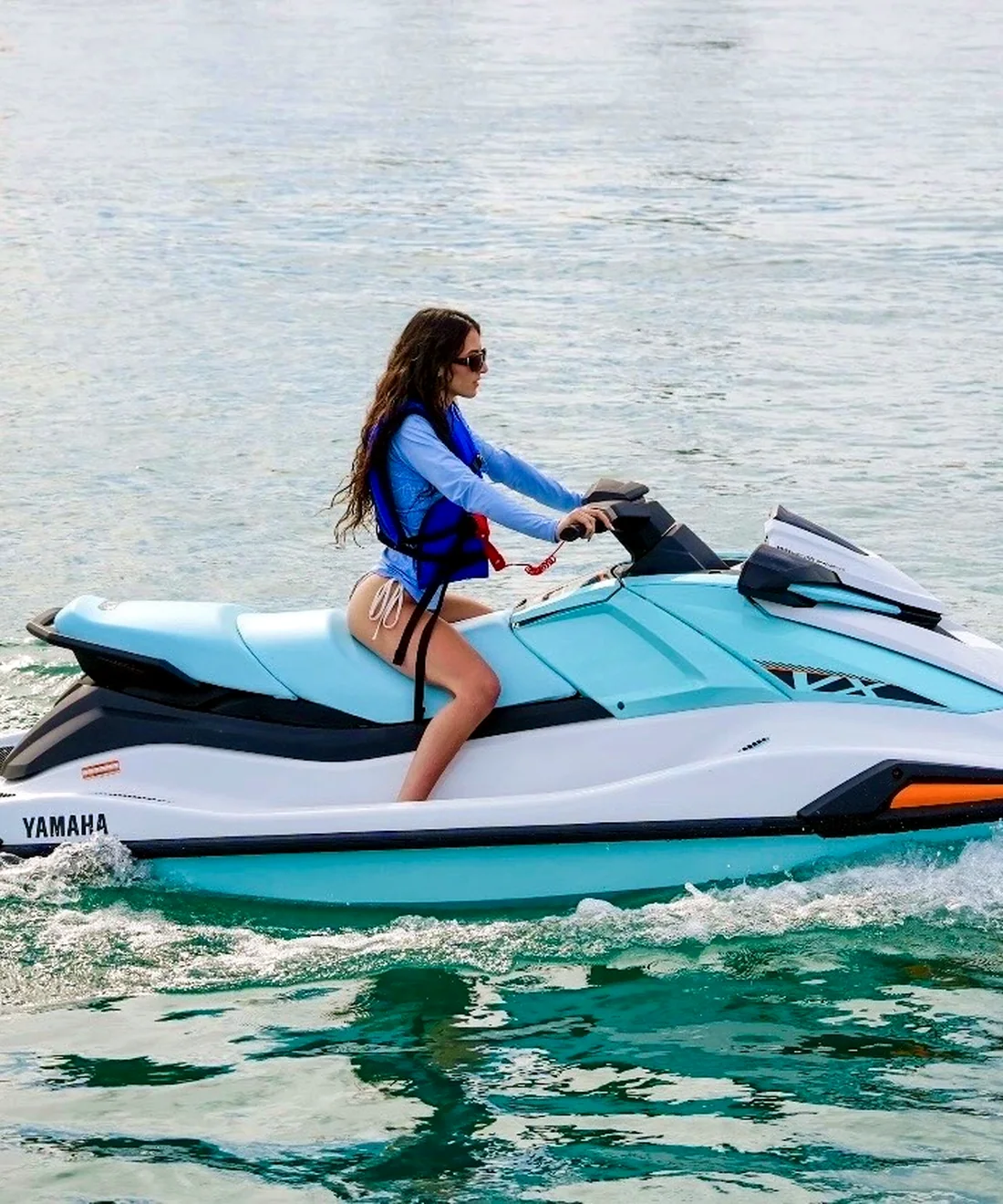 A rider on a turquoise jet ski crossing Lake Michigan.